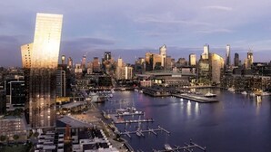 A cityscape with a prominent modern building, a marina with boats, and a variety of other high-rise buildings.