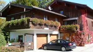 A two-story wooden house with a car parked in front.