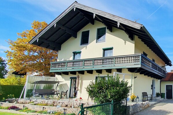 A two-story house with a balcony, a covered patio, and a garden area.
