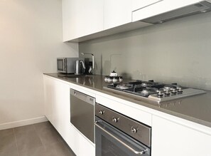 Enjoy cooking in this well-equipped kitchen with a stainless steel stove, microwave, and kettle.