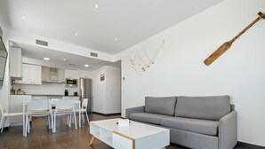 A modern living room with a grey sofa, white coffee table, and white chairs. - Penthouse with private solarium and pool sea views (L'Ametlla de Mar)
