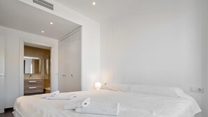A modern hotel room with a large bed, a bathroom with a mirror, and a bedside table. - Penthouse with private solarium and pool sea views (L'Ametlla de Mar)