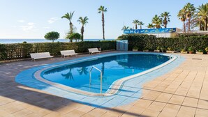 Ein Swimmingpool mit Liegestühlen, einer Snackbar und Blick aufs Meer.