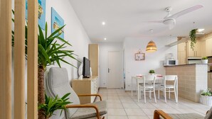 Ein modernes Wohnzimmer mit einer Couch, einem Fernseher und einem Essbereich mit Tisch und Stühlen.