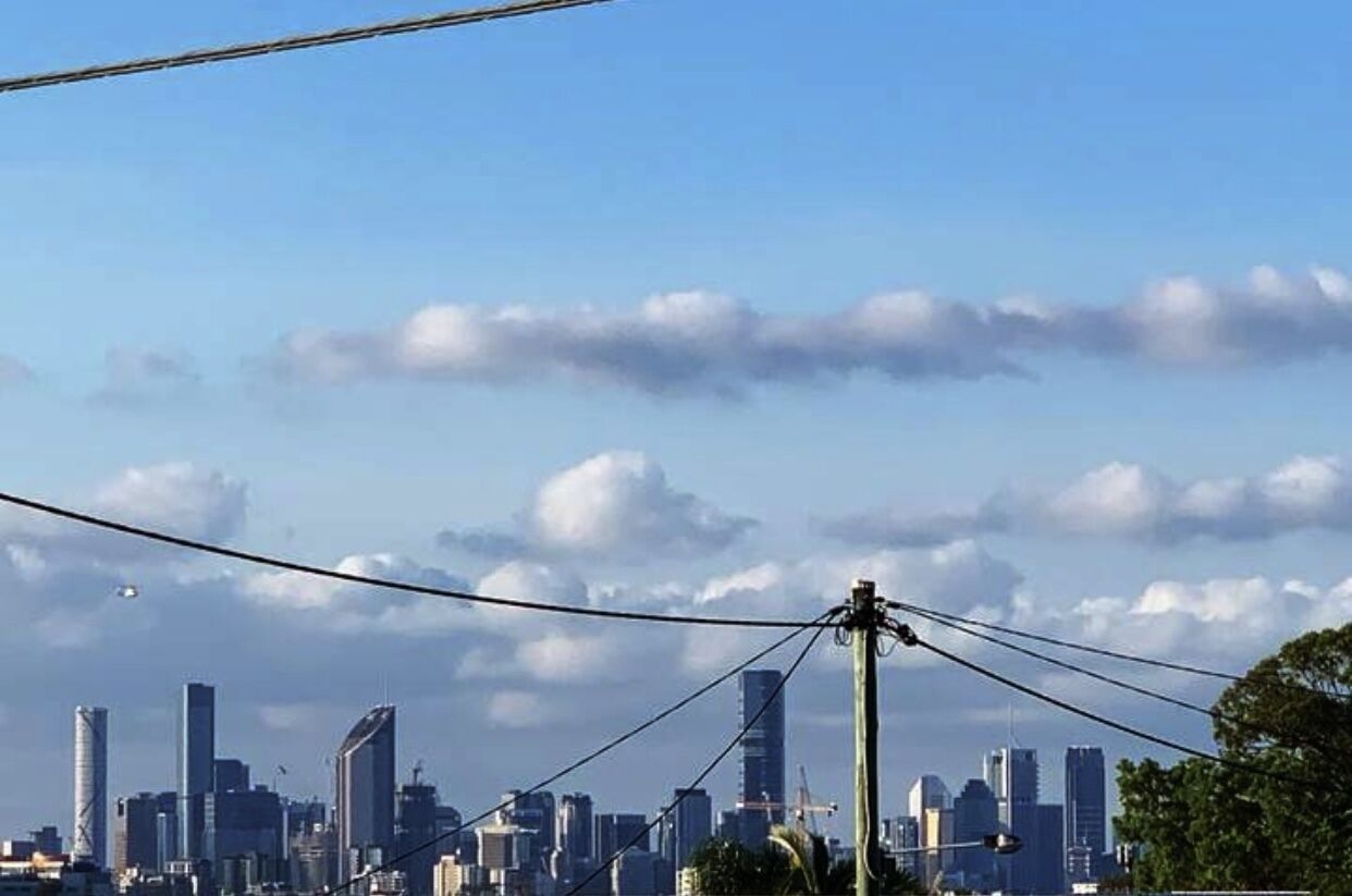 A city skyline with modern high-rise buildings under a partly cloudy sky.