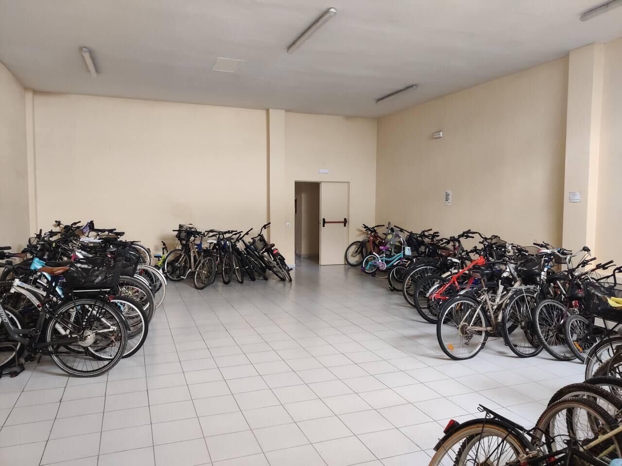Un vaste espace intérieur où de nombreux vélos sont rangés le long des murs.
