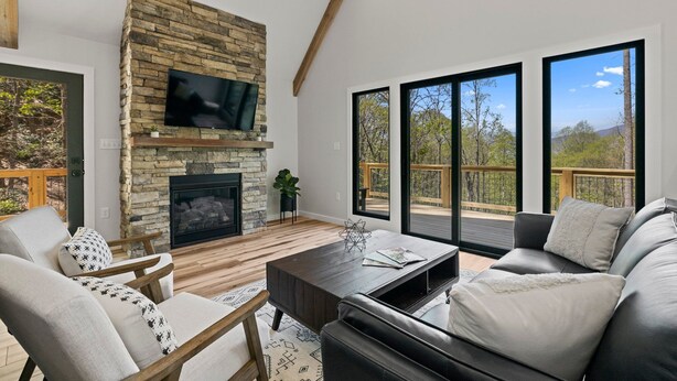 Ein modernes Wohnzimmer mit Kamin aus Stein, großen Fenstern und einem Balkon.
