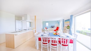 A modern kitchen with white cabinets and a dining area with a table set for four. - Villa Amalfi (Miyakojima)