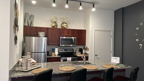 A modern kitchen with stainless steel appliances, wooden cabinets, granite countertops, and a built-in microwave. - Honeymoon, The City of Music, king s Bed, B street (Memphis)