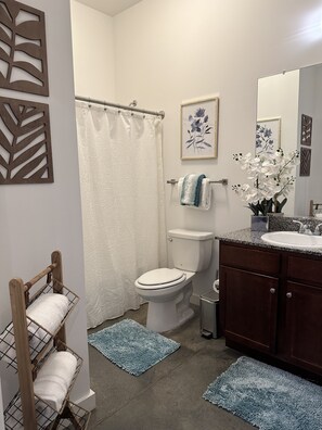 A bathroom with a toilet, sink, and shower curtain. There are towels on a rack and a plant on the counter. - Honeymoon, The City of Music, king s Bed, B street (Memphis)