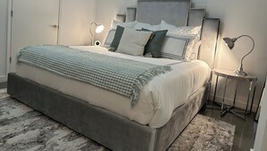 A neatly arranged bedroom with a large bed, bedside lamps, and a small table with a lamp. - Honeymoon, The City of Music, king s Bed, B street (Memphis)