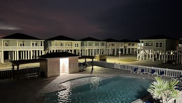 Relax by the pool surrounded by a fence and lounge chairs.