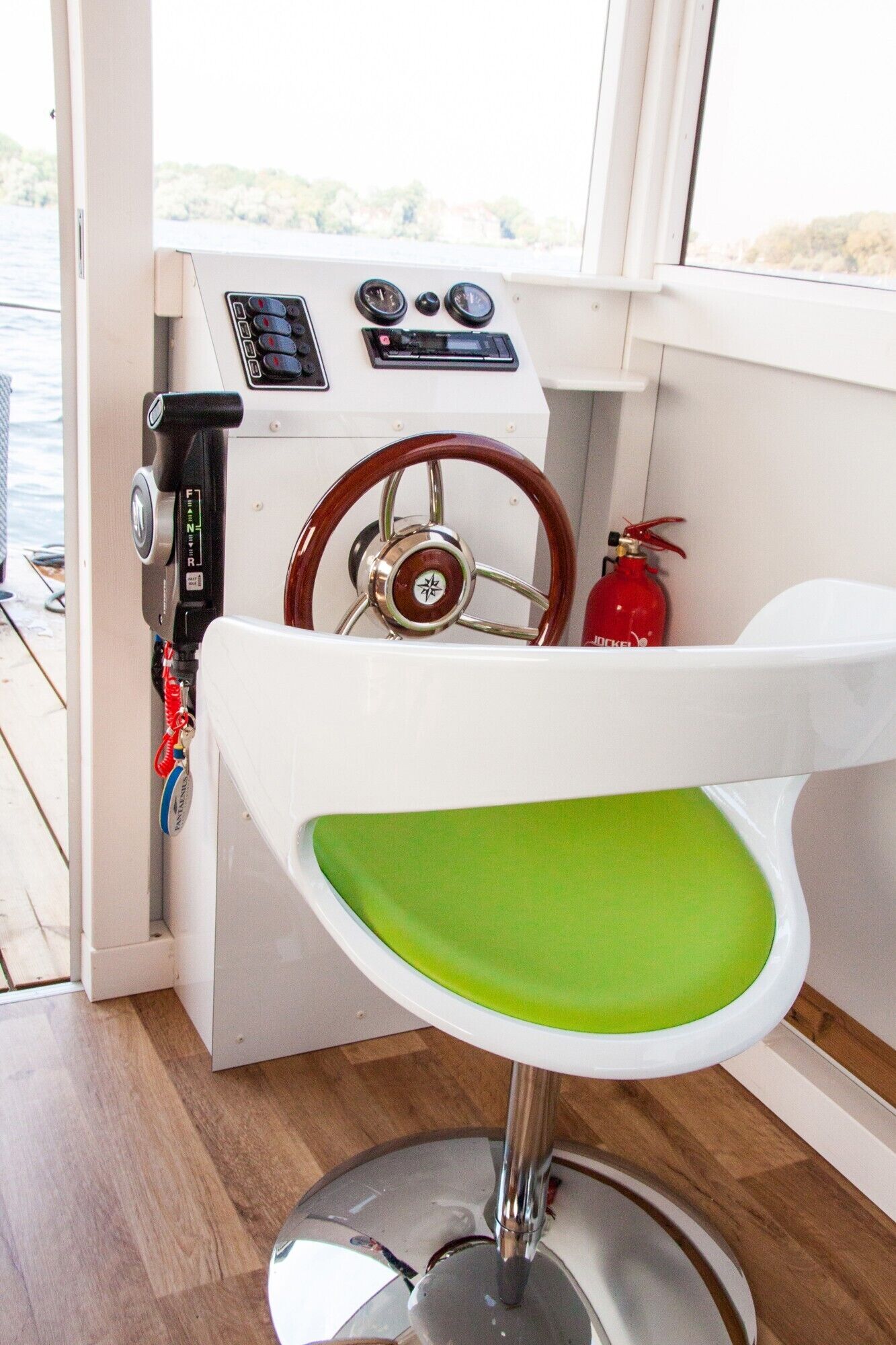A boat's interior with a steering wheel, control panel, and a green cushioned seat.