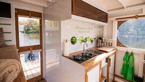 A compact kitchen with a window view of a river, a sink, and a stove. - Fully-Equipped Boat 'Lisa' with Terraces (Priepert)