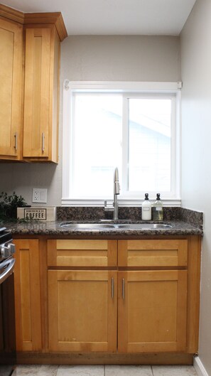 A kitchen with wooden cabinets, a stainless steel sink, and a window above the sink. - Cozy 2b2b Home in Central San Jose (San Jose)