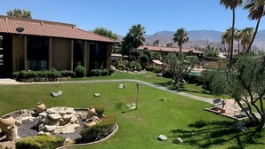 Un resort con piscina, palmeras y montañas al fondo.