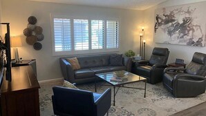 Una sala de estar con sofá, sillones, una mesa de centro y alfombra.