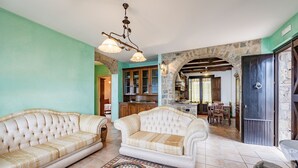 A spacious living room with a sofa, a patterned rug, and a stone archway leading to a kitchen. - Beautiful Apt With Seaview Terrace, Pisciotta, Italy (Pisciotta)