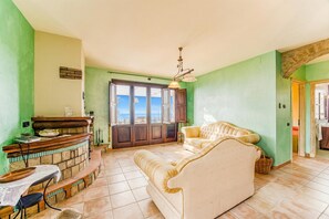 A living room with a sofa, a small table, a stone fireplace, and a view through a door.