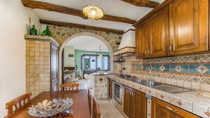 A kitchen with wooden cabinets, a tiled backsplash, and a stone archway. - Beautiful Apt With Seaview Terrace, Pisciotta, Italy (Pisciotta)