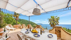 An outdoor dining area with a table set for two, surrounded by white chairs, with a view of the sea and hills. - Beautiful Apt With Seaview Terrace, Pisciotta, Italy (Pisciotta)