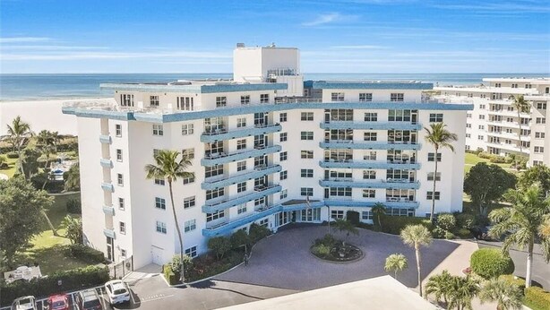 A multi-story hotel with a central courtyard, balconies, and a view of the beach.