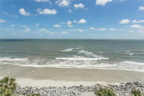 A beach with a rocky shoreline and calm waves. - 1112 Ocean Boulevard (Saint Simons Island)