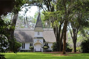 A church with a steeple, surrounded by trees and a well-maintained lawn. - 1112 Ocean Boulevard (Saint Simons Island)