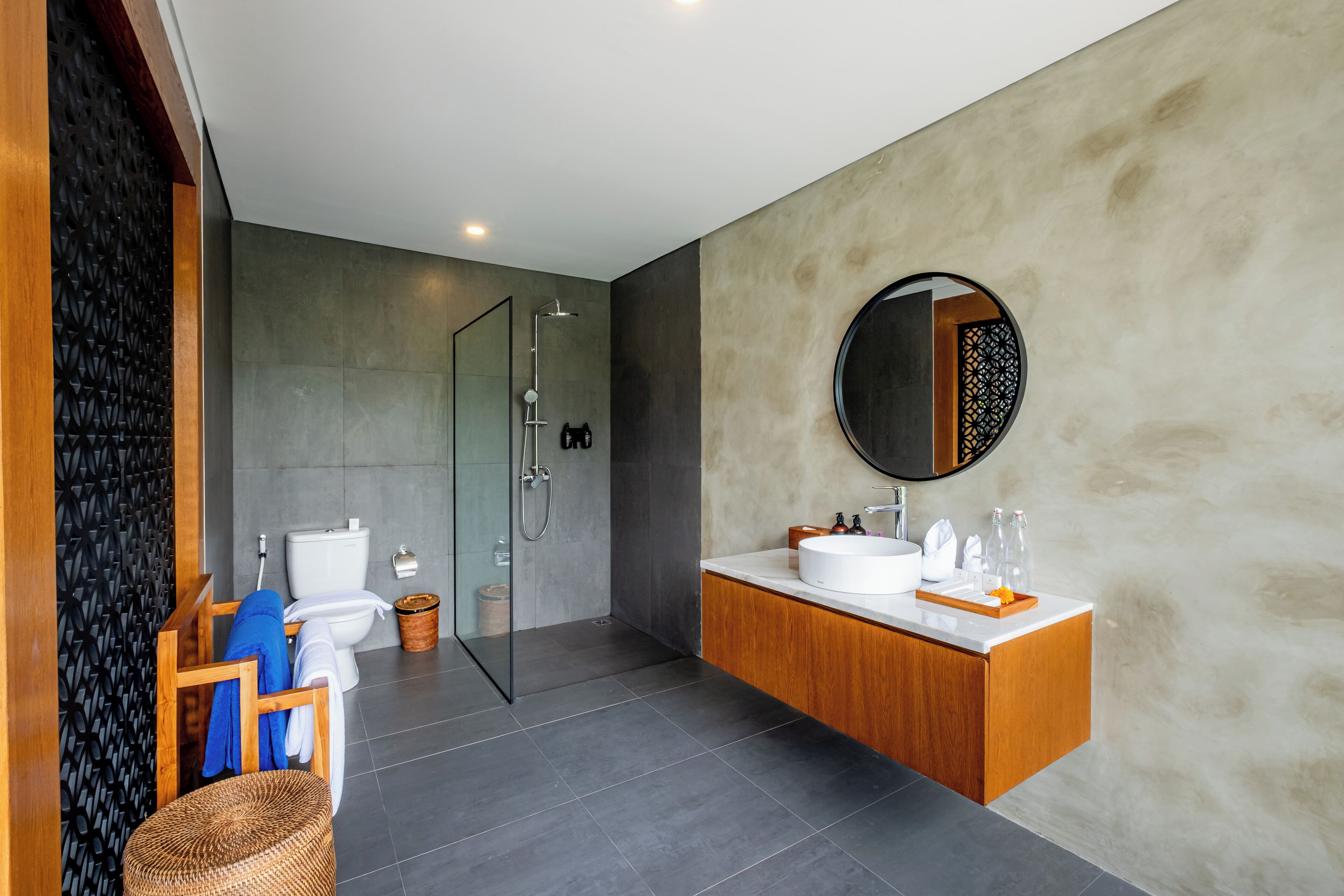 A modern bathroom with a glass shower enclosure, a wooden vanity, and a large mirror.