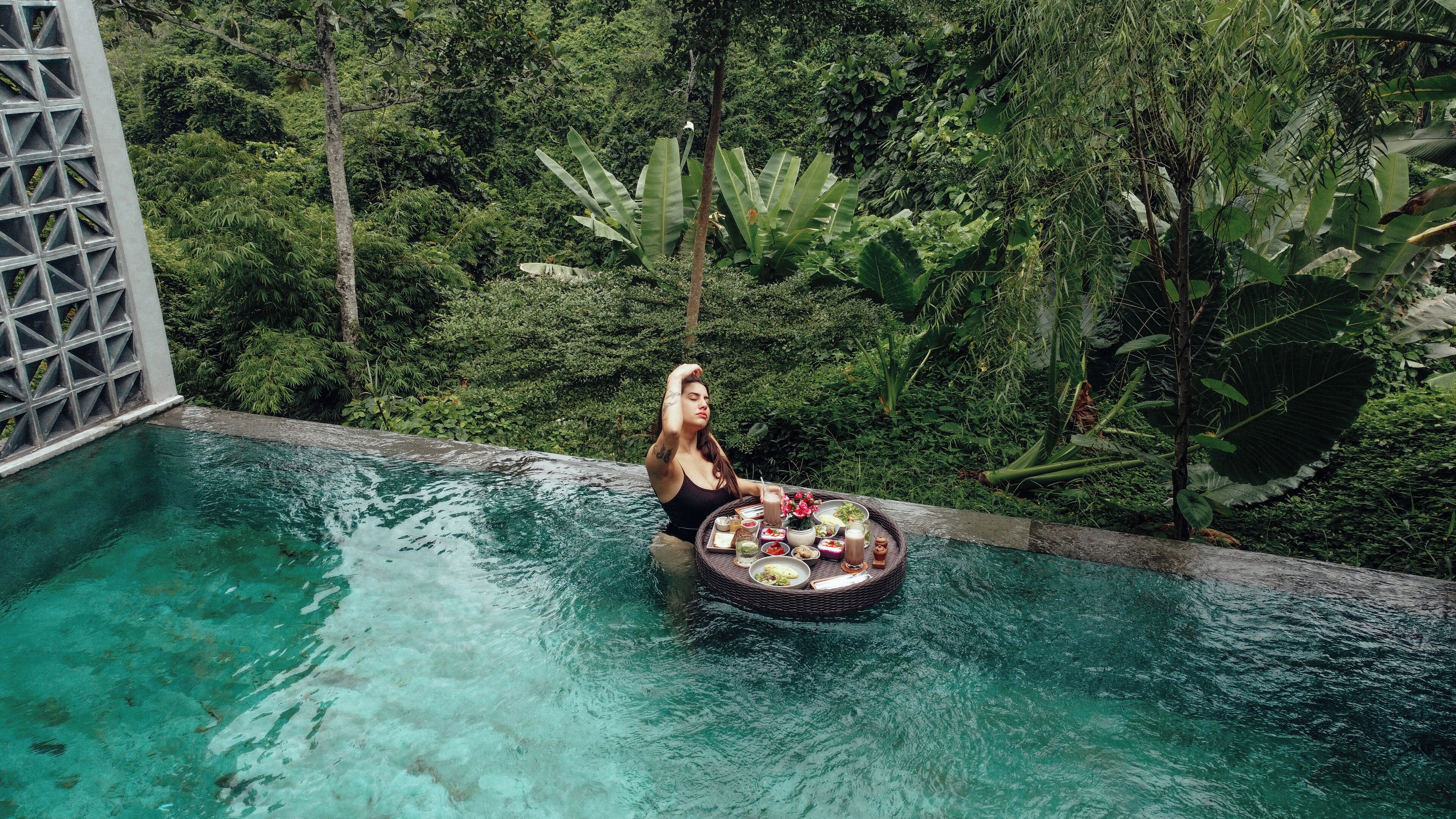 A person in a pool surrounded by lush greenery.
