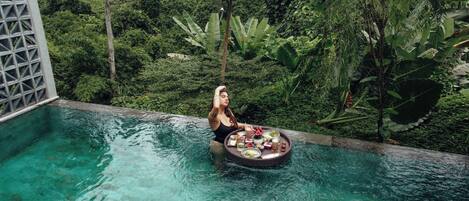 A person in a pool surrounded by lush greenery.