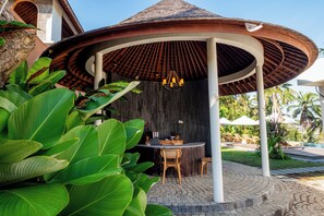 A covered outdoor seating area with a round table, chairs, and a hanging light fixture. - LeRosa Valley Resort (Ubud)