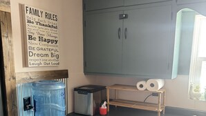 Eine Küche mit Wasserspender, Toaster und einem Schrank, an dem ein Handtuch hängt.