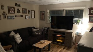 Ein Wohnzimmer mit Kamin, Fernseher und einer Couch.