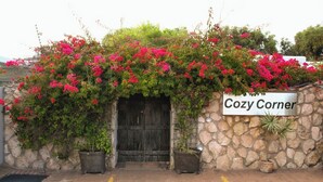 A stone wall with a sign reading 'Cozy Corner,' a wooden door, and potted plants. - Cozy Crner, home away from home, mere 100m away from pristine beaches (Langebaan)