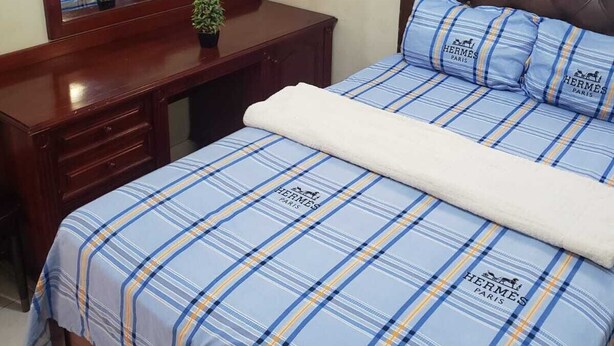 A bedroom with a bed, a wooden nightstand, a mirror, and a blue curtain. - Jacaranda Vacation Home (Spanish Town)