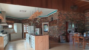 Une cuisine spacieuse avec des meubles en bois, un îlot central et un mur d’accent en briques.