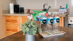 A kitchen with wooden cabinets, a countertop with water bottles, a coffee maker, and a potted plant. - The Hideaway cozy , centrally located apartment 3 minutes from town center (Mandeville)