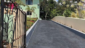 A two-story building with a gated entrance, surrounded by lush greenery and palm trees. - The Hideaway cozy , centrally located apartment 3 minutes from town center (Mandeville)