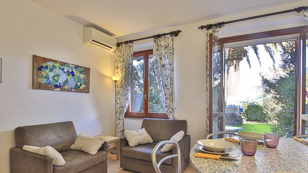 Una sala acogedora con un sofá, una mesa de comedor con una silla y una ventana con cortinas.