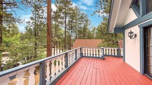 A wooden deck with a railing, surrounded by tall pine trees. - Centrally Located large 3 Bedrm/Available EV Charg
 (Big Bear Lake)