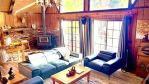 A rustic cabin interior with a fireplace, leather sofas, and a large window. - Centrally Located large 3 Bedrm/Available EV Charg
 (Big Bear Lake)