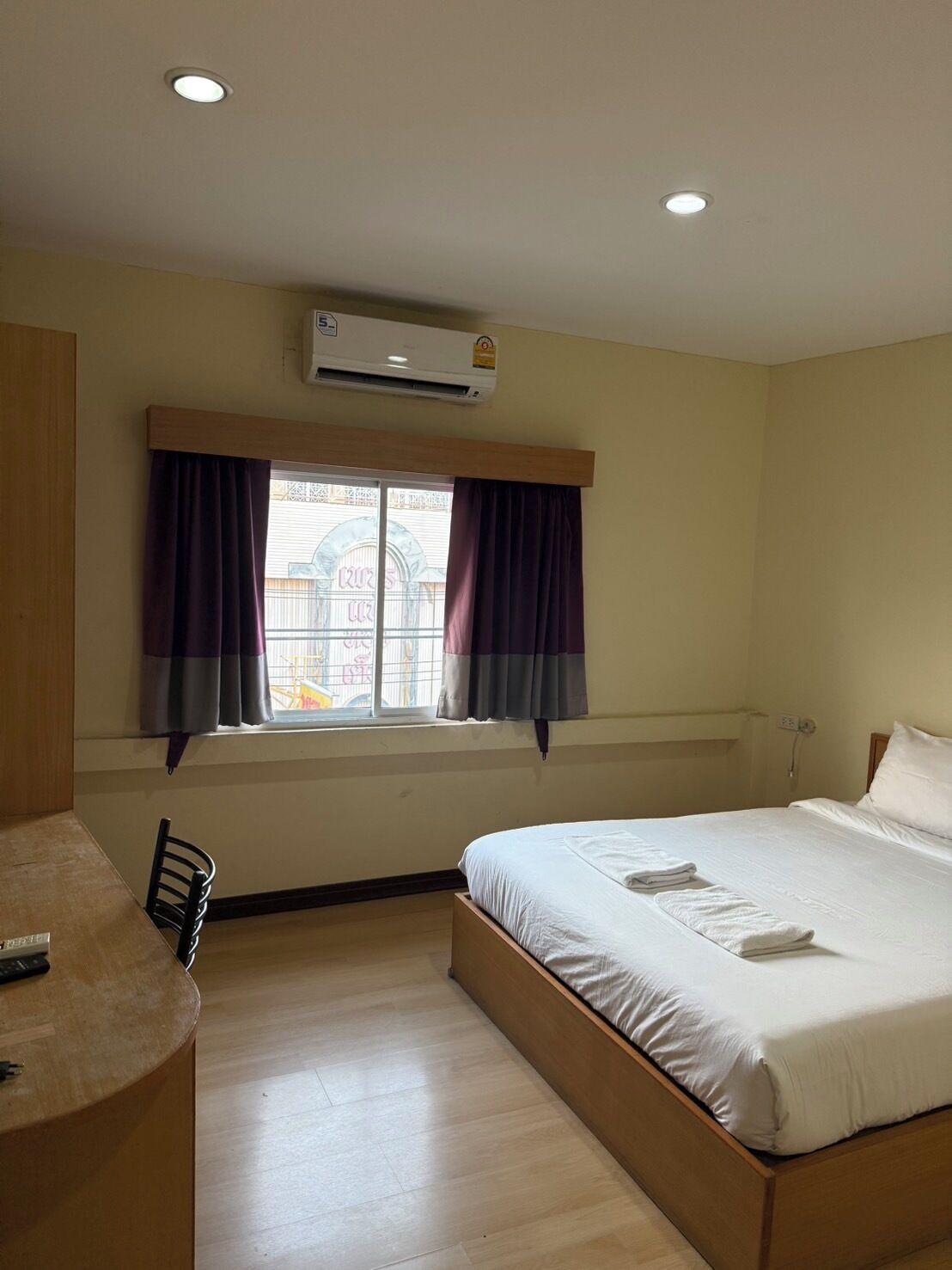 A hotel room with a single bed, a desk, and a window with curtains.