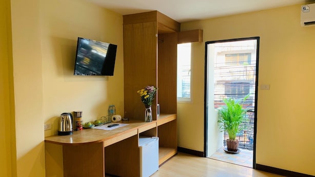 Una habitación moderna con un escritorio de madera, un televisor de pantalla plana, una planta en maceta y vistas al exterior.