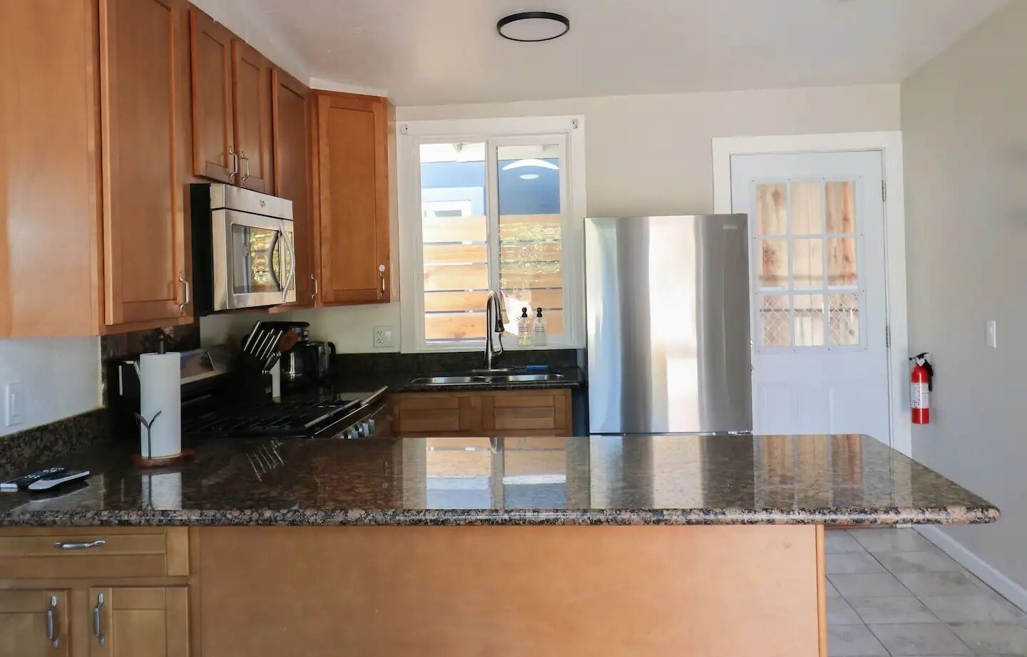 A kitchen with wooden cabinets, a stainless steel refrigerator, and a granite countertop.