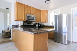 A kitchen with wooden cabinets, a stainless steel refrigerator, and a granite countertop.