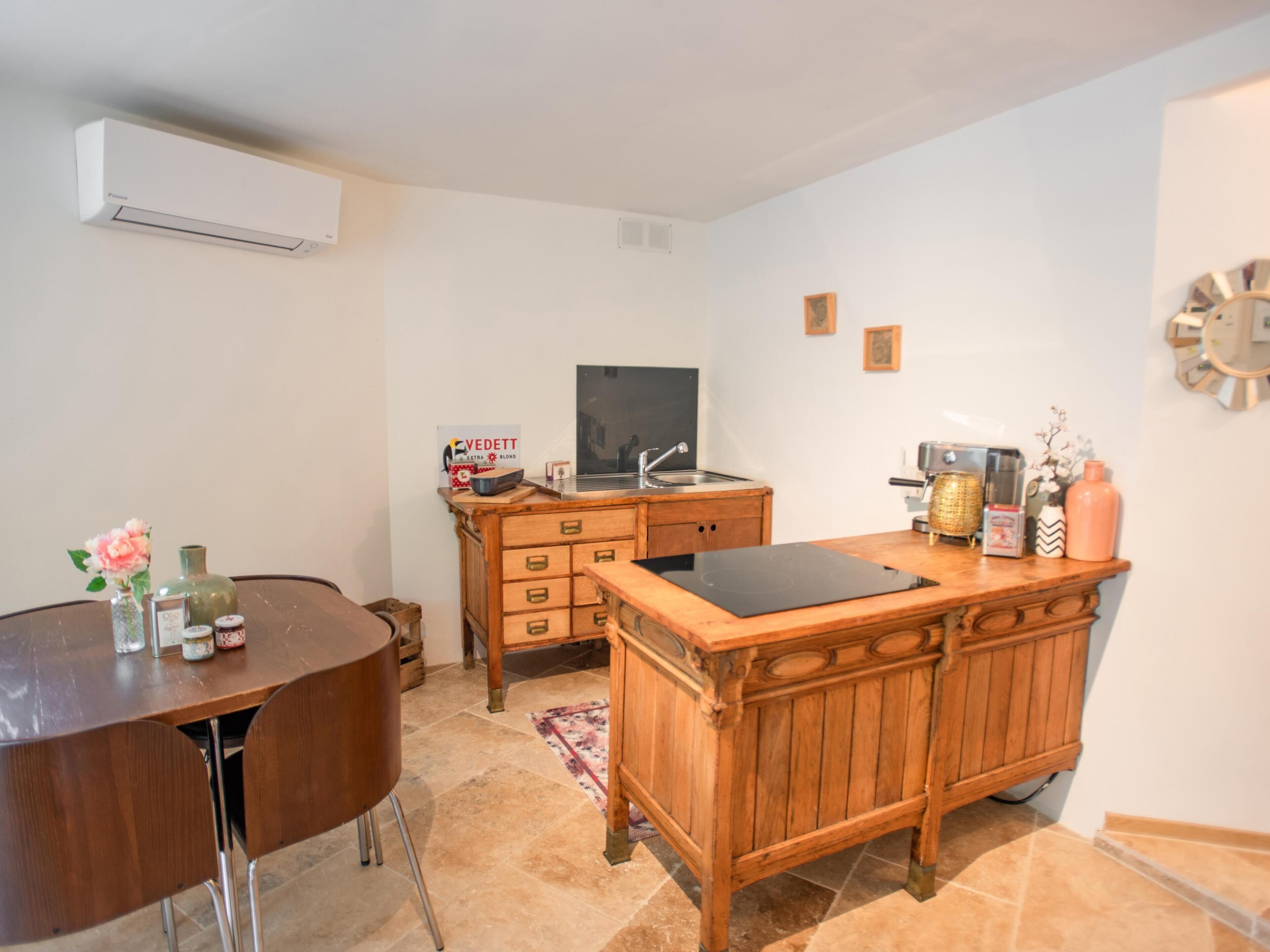 A compact kitchen with a wooden countertop, a built-in oven, a sink, and a small dining area with a round table and chairs.