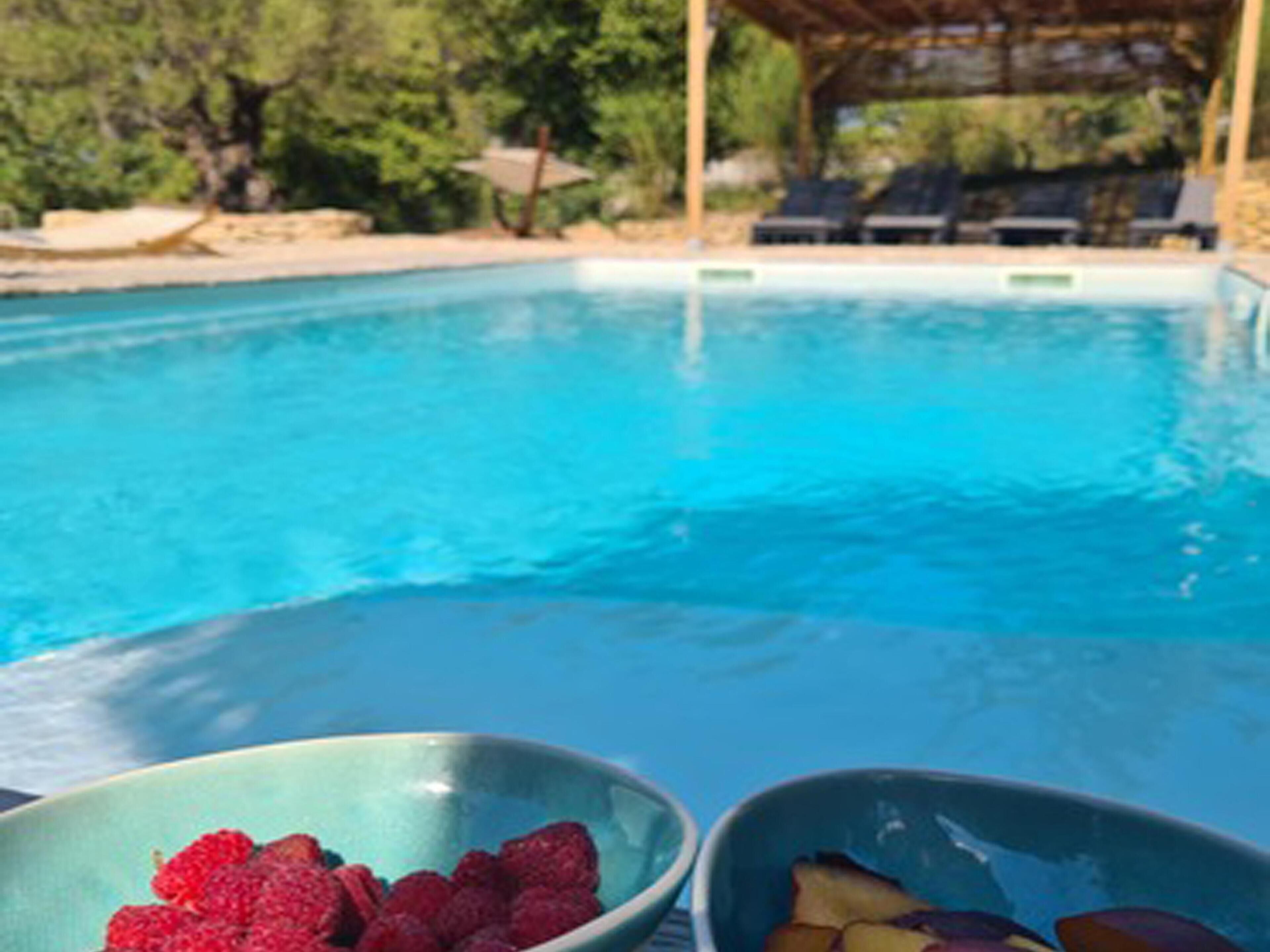 A pool with two bowls of fruit on the edge.