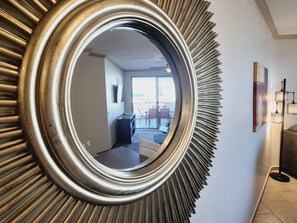 A mirror with a sunburst frame reflecting a room with a staircase, a dining area, and a view of the outdoors. - Condo with View of El Malecón (Puerto Peñasco)
