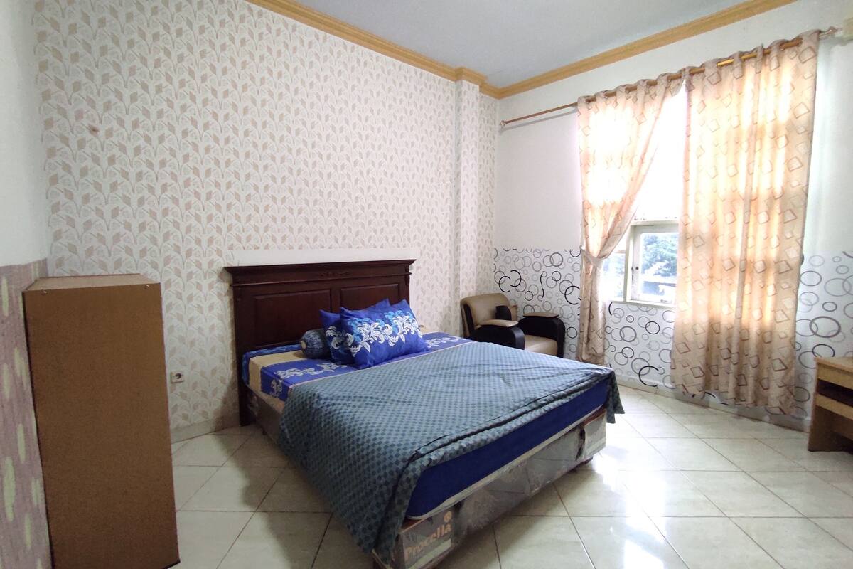 A bedroom with a bed, a chair, and a wardrobe.